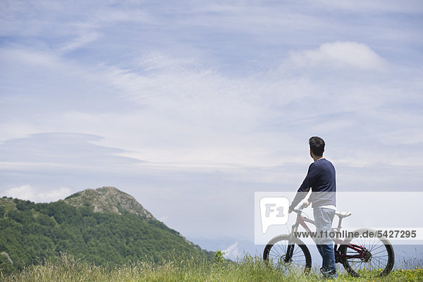 Man standing by mountain bike  enjoying scenic mountain view  rear view
