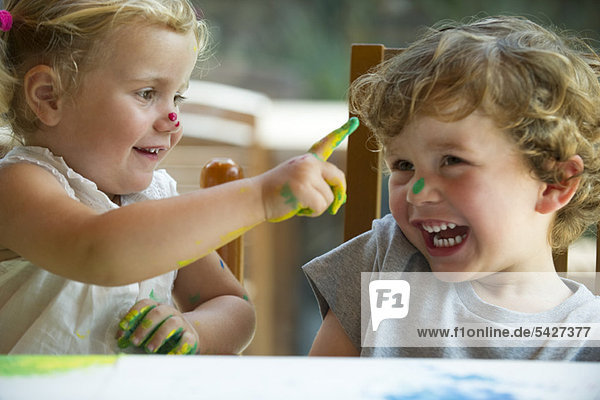 Little girl wiping paint on her brother's nose