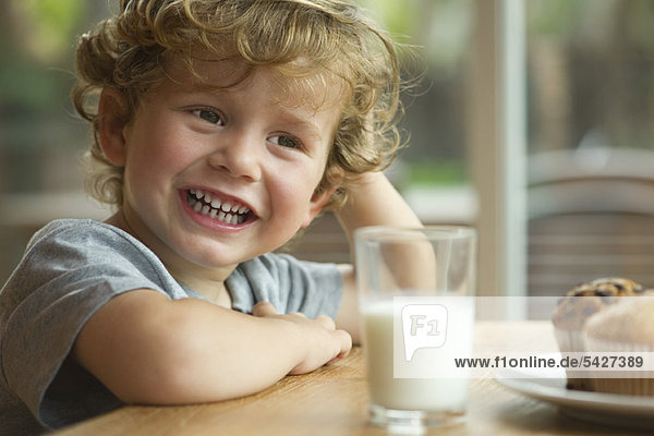 Kleiner Junge am Tisch sitzend mit Snack  Portrait