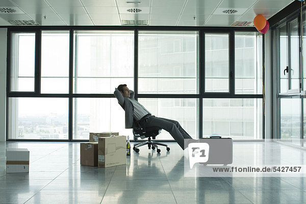 Geschäftsmann sitzend in leerem Büro mit Kisten auf dem Boden