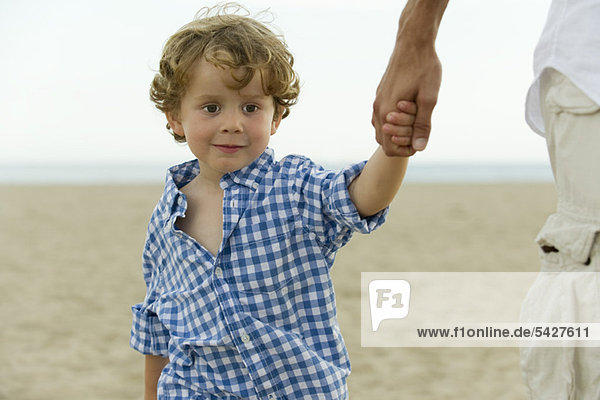 Kleiner Junge hält Vaters Hand am Strand  abgeschnitten