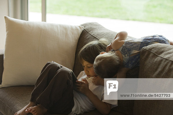 Junge entspannt auf dem Sofa  schaut auf digitales Tablett