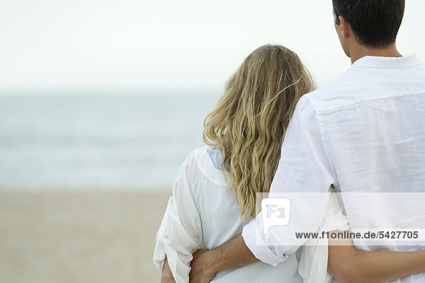 Paar steht zusammen am Strand  Rückansicht