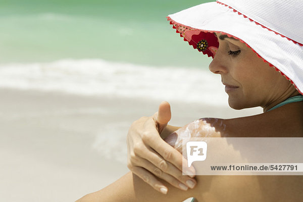 Woman at the beach applying sunscreen
