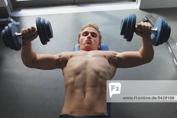 Young Man Taking Physical Training with Dumbbells
