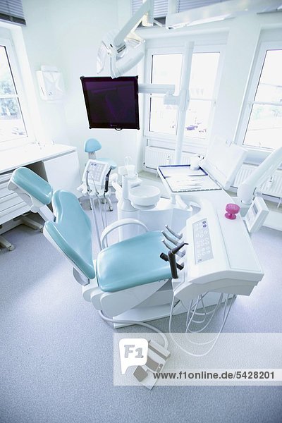 Blick in Behandlungszimmer mit Behandlungsstuhl und Konsole mit Spray und Winkelstücken in Zahnarztpraxis