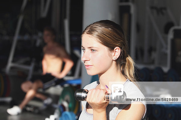 Young Woman Taking Physical Training with Dumbbell