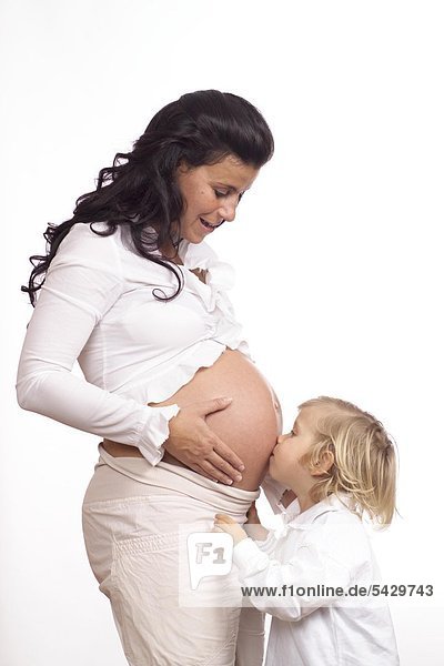 Kind küsst den Bauch einer schwangeren Frau