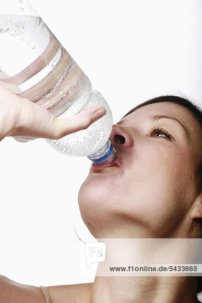Portrait einer jungen Frau die Wasser aus einer PET- Flasche trinkt - a woman is drinking water