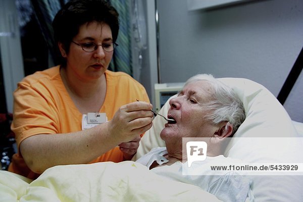 Pflegerin füttert eine alte Frau - Betreuung demenzkranker Patientinnen -