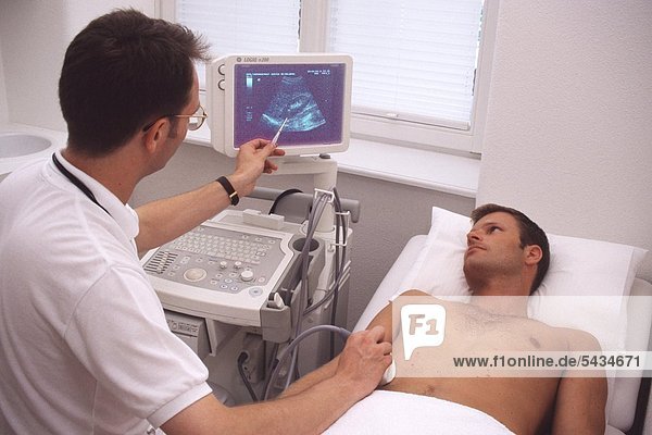 Arzt führt bei einem männlichen Patienten eine Ultraschall-Untersuchung des Bauchraumes - der Niere - durch