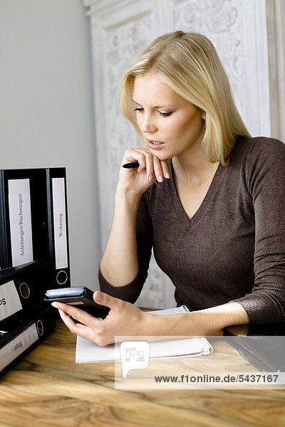 Ernste blonde Frau schaut auf einen Taschenrechner