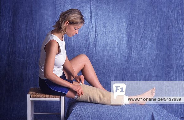 Junge Frau legt für einen Kniewickel die 3. Wickellage an