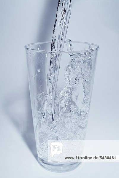 Wasserschwall fliesst in ein Glas  Bewegung eingefroren