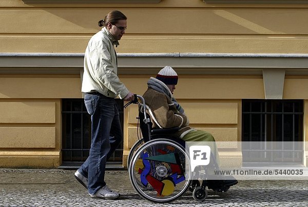 Zivildienstleistender mit einem Behinderten - Down-Syndrom - im Rollstuhl