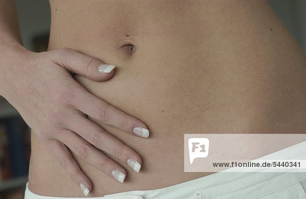 Nah Detail - flacher Bauch mit schlanker Hand von einer jungen gepflegten Frau