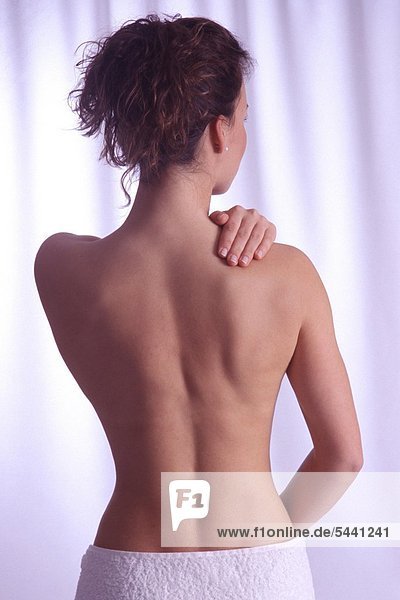 Rückenansicht - Junge Frau hält eine Hand an ihre Schulter