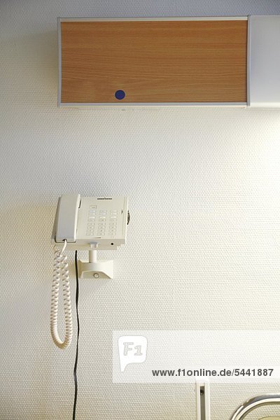 Krankenzimmer  ein Telefon hängt an der Wand neben einem Krankenbett.