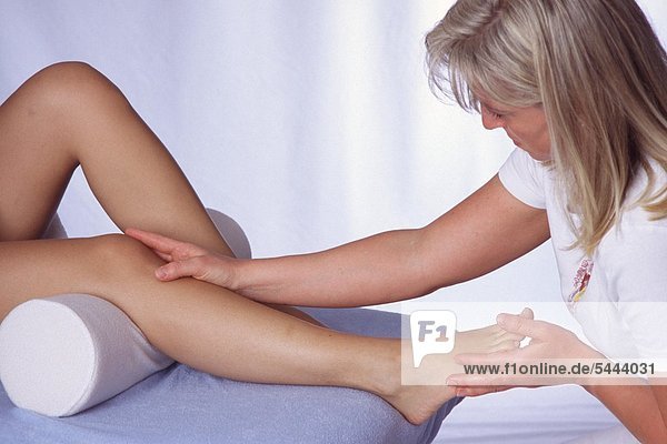 Junge Frau wird am Fuß mit einer Fußreflexzonenmassage behandelt