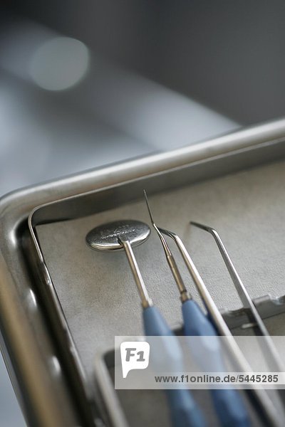 Zahnarztpraxis : Eine Pinzette   eine Sonde und ein Mundspiegel liegen auf einem Tablett.