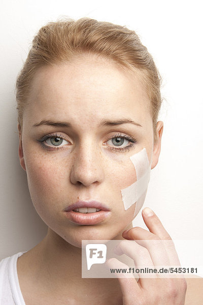 Young woman with plaster in her face