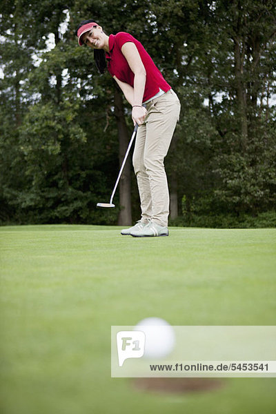 Eine Golferin beim Putten  Golfball am Lochrand