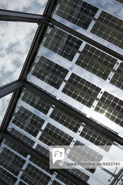 Unter einer Reihe von Solarmodulen auf einem offenen Dach mit Himmel im Hintergrund