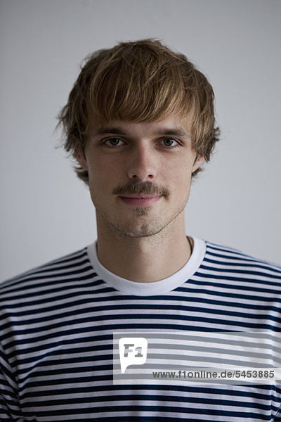A hip young man wearing a striped t-shirt  looking at camera