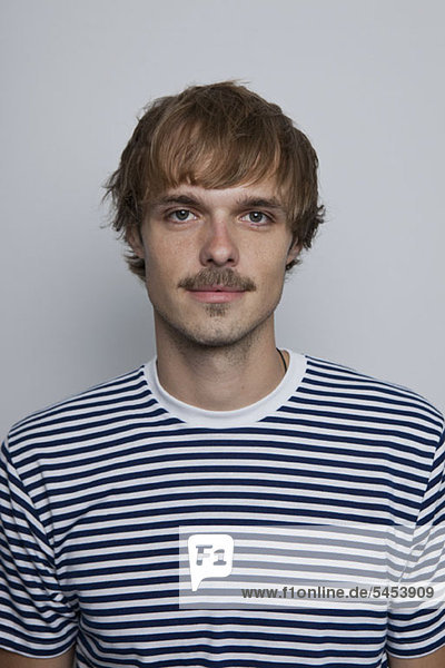 A young man with a mustache wearing a striped t-shirt