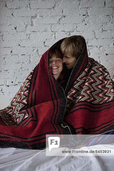 Ein junges glückliches Paar in eine Decke gewickelt.
