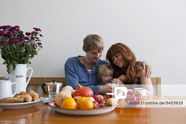A young family sitting side by side having breakfast