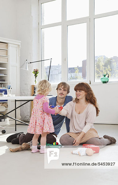 A young girl and her parents playing with toys