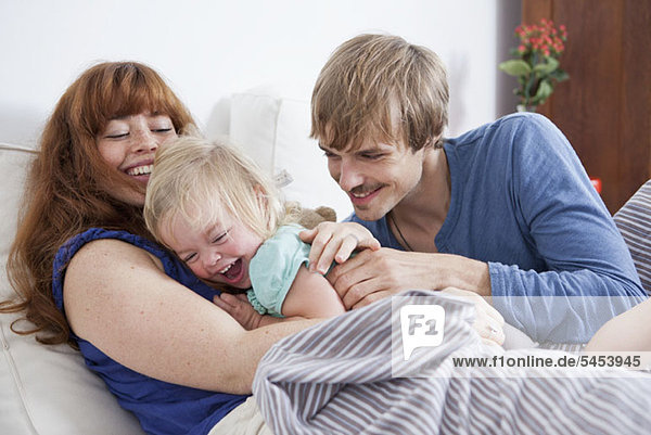 A young family having playful fun in bed