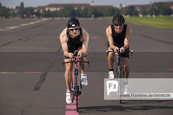 Two cyclists on racing bicycles cycling on a marked road