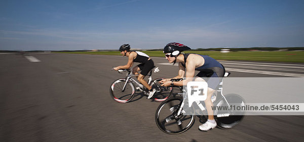 Two cyclists on racing bicycles  side view  low angle view