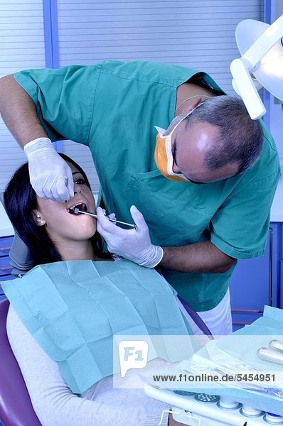 Patientin bei Zahnbehandlung mit Zahnarzt und Helferin