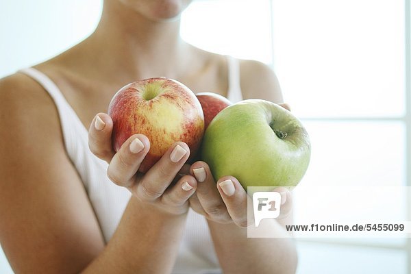 Frau hält drei Äpfel