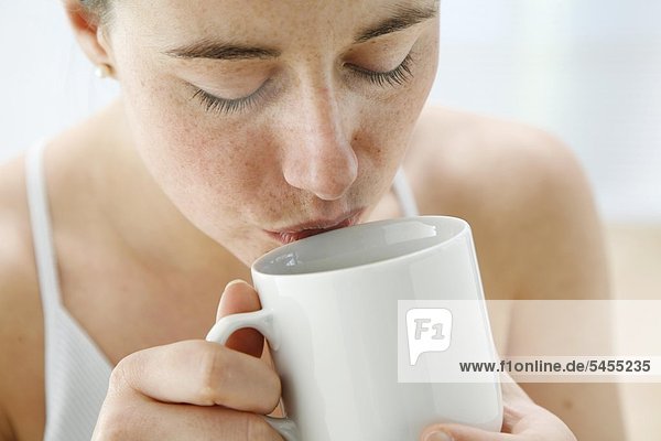 Nah Portrait - junge Frau trinkt genußvoll Tee aus Teetasse