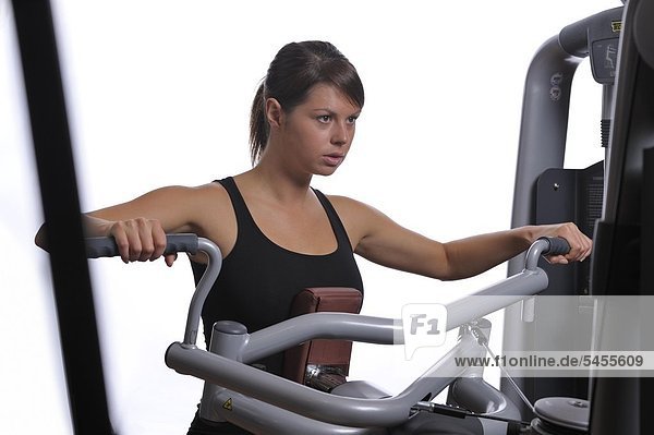 Junge Frau im Fitnessstudio   Training der Arm- und Brustmuskulatur