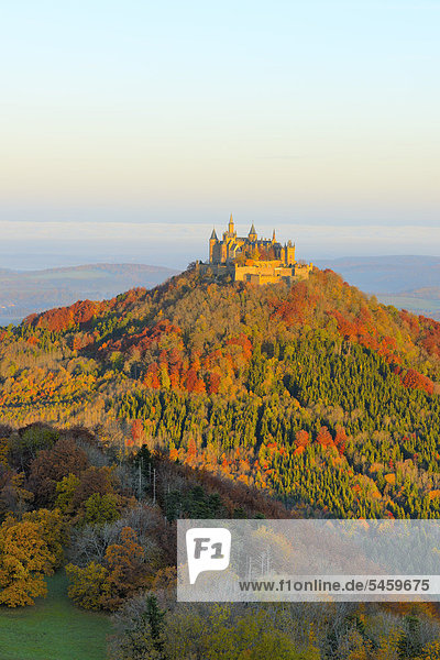 Burg Hohenzollern Castle in the early morning light with autumnal forest  early morning fog  Swabian Alb  Baden-Wuerttemberg  Germany  Europe