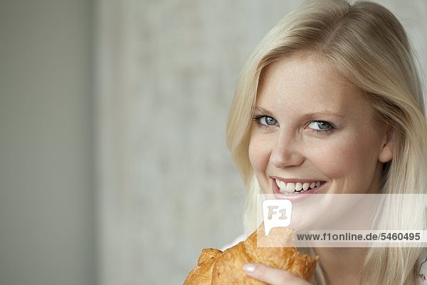 Junge Frau isst ein Croissant