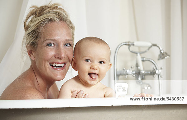 Smiling mother bathing with baby