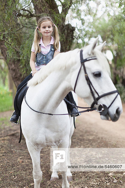 Smiling girl riding horse in park