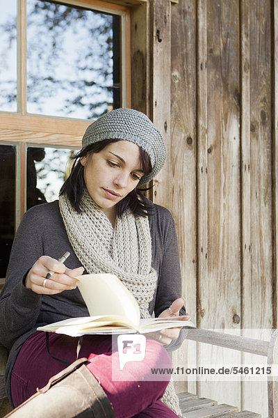 Frau schreibt im Notizbuch auf der Veranda