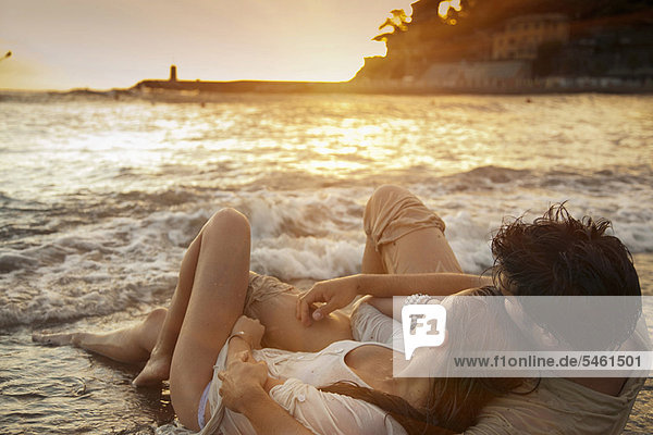 Paar auf Sand am Strand liegend