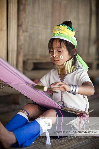 Girl in traditional dress weaving at loom
