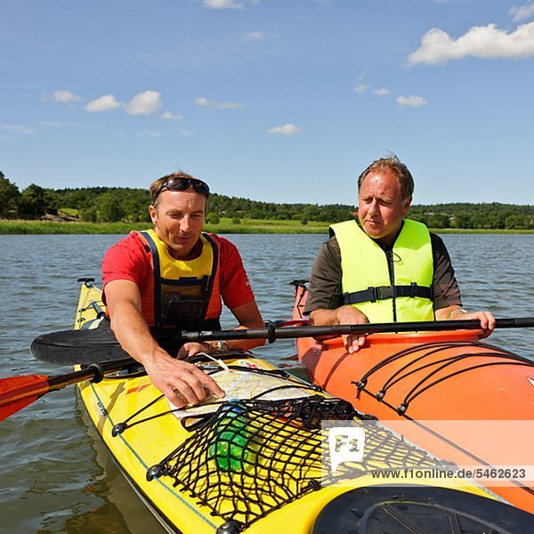 Two men in kayak looking on a map