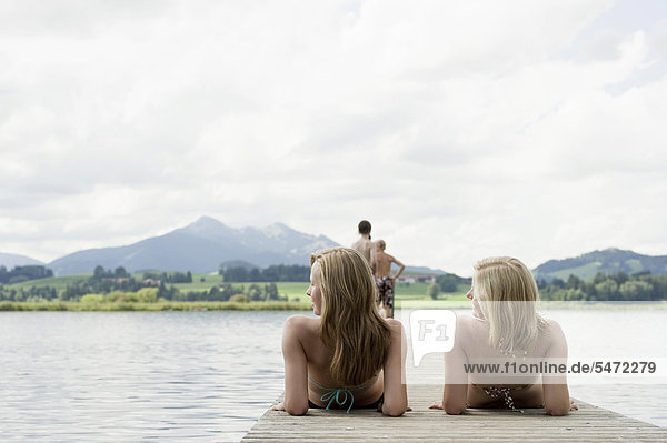 Two women lying on a wooden jetty  lake Hopfensee near Fuessen  Allgaeu  Bavaria  Germany  Europe