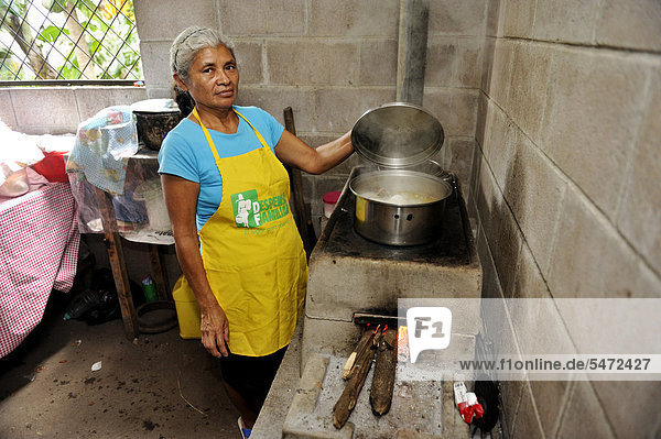 Köchin hebt den Deckel eines Topfes  sie kocht mit einem energiesparenden Herd  Gemeinde Cerro Verde  El Salvador  Zentralamerika  Lateinamerika
