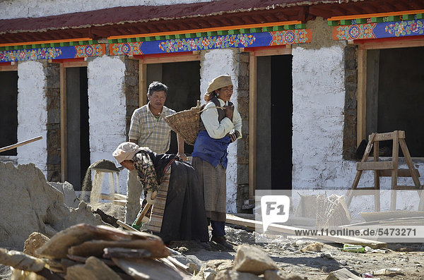 Tibetan craftsmen  women in traditional dress and men  during construction of a traditional Tibetan building  Pundo  Reting  Himalayas  Lhundrup district  central Tibet  Tibet  China  Asia